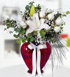 Kalpli Vazoda Beyaz Güller ve Lilyum Kırmızı kalp cam vazo içerisinde beyaz lilyum, beyaz gül, cipsofilya ve yeşillikler ile hazırlanmıştır.